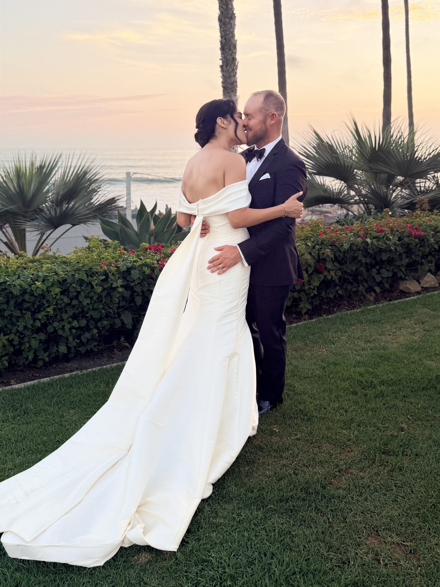 Bride and groom kissing at sunset in garden with palm trees