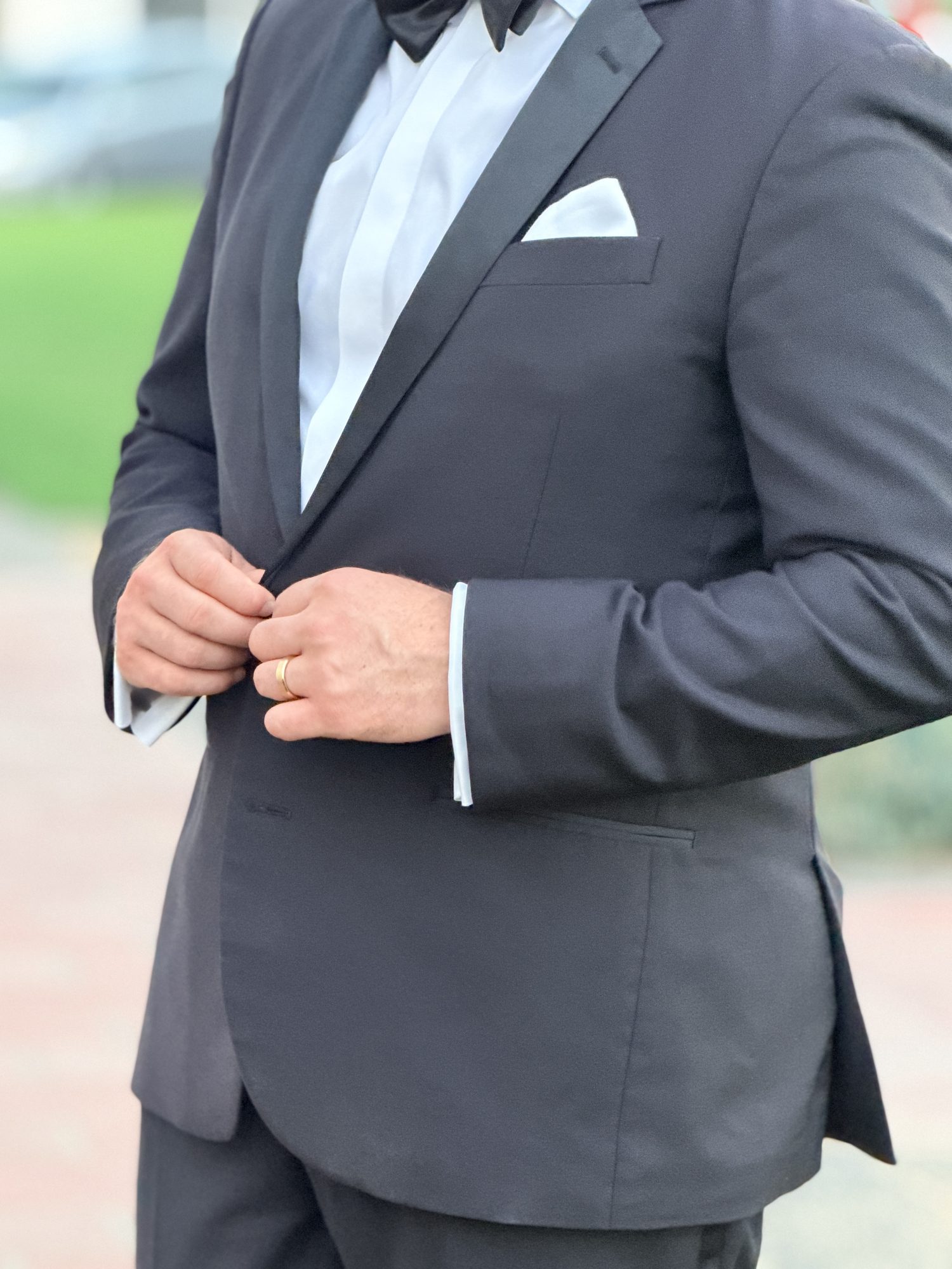 Groom buttoning his tuxedo jacket, close-up detail
