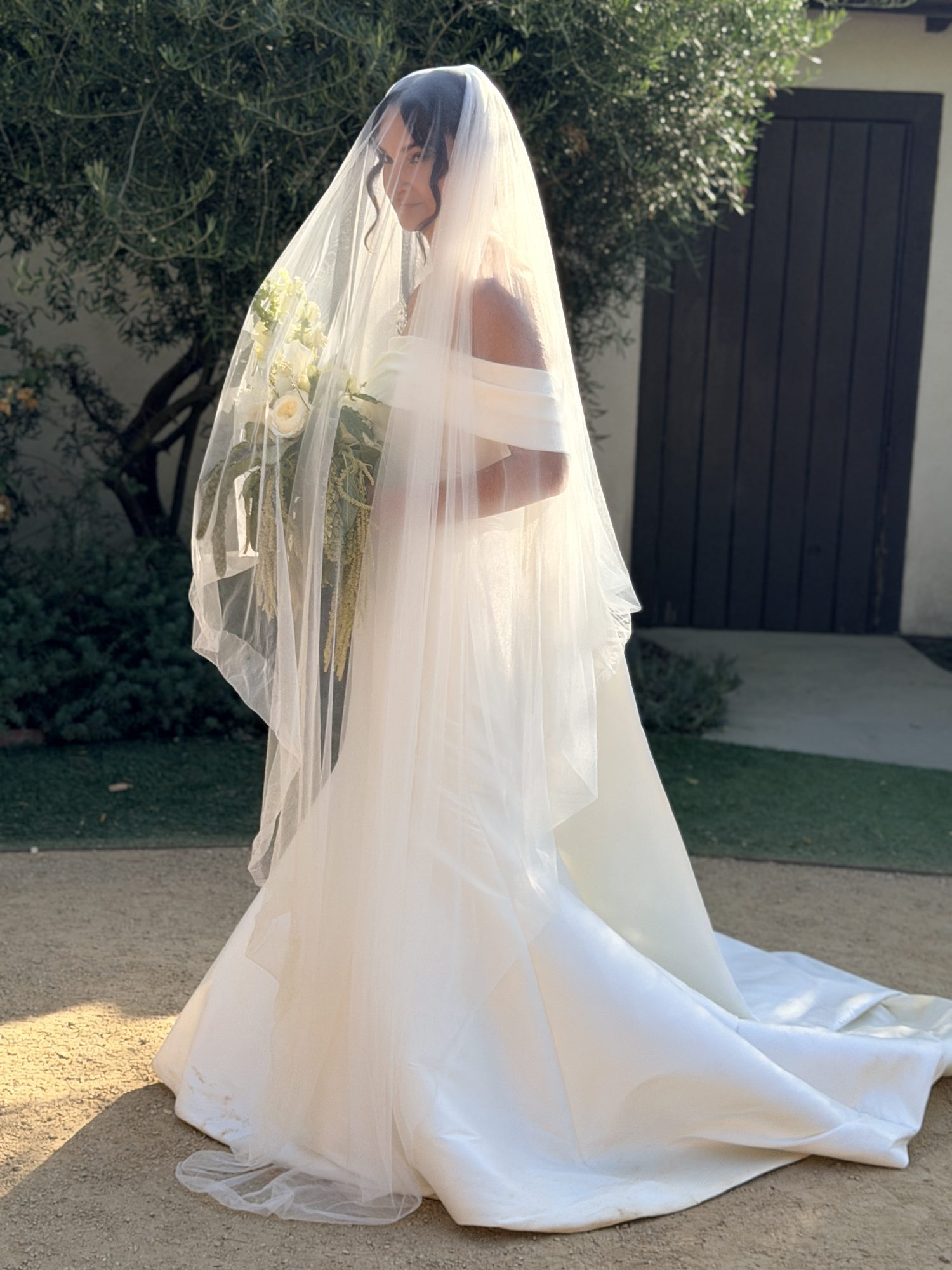 Bride's veil flowing in the wind, bouquet in hand