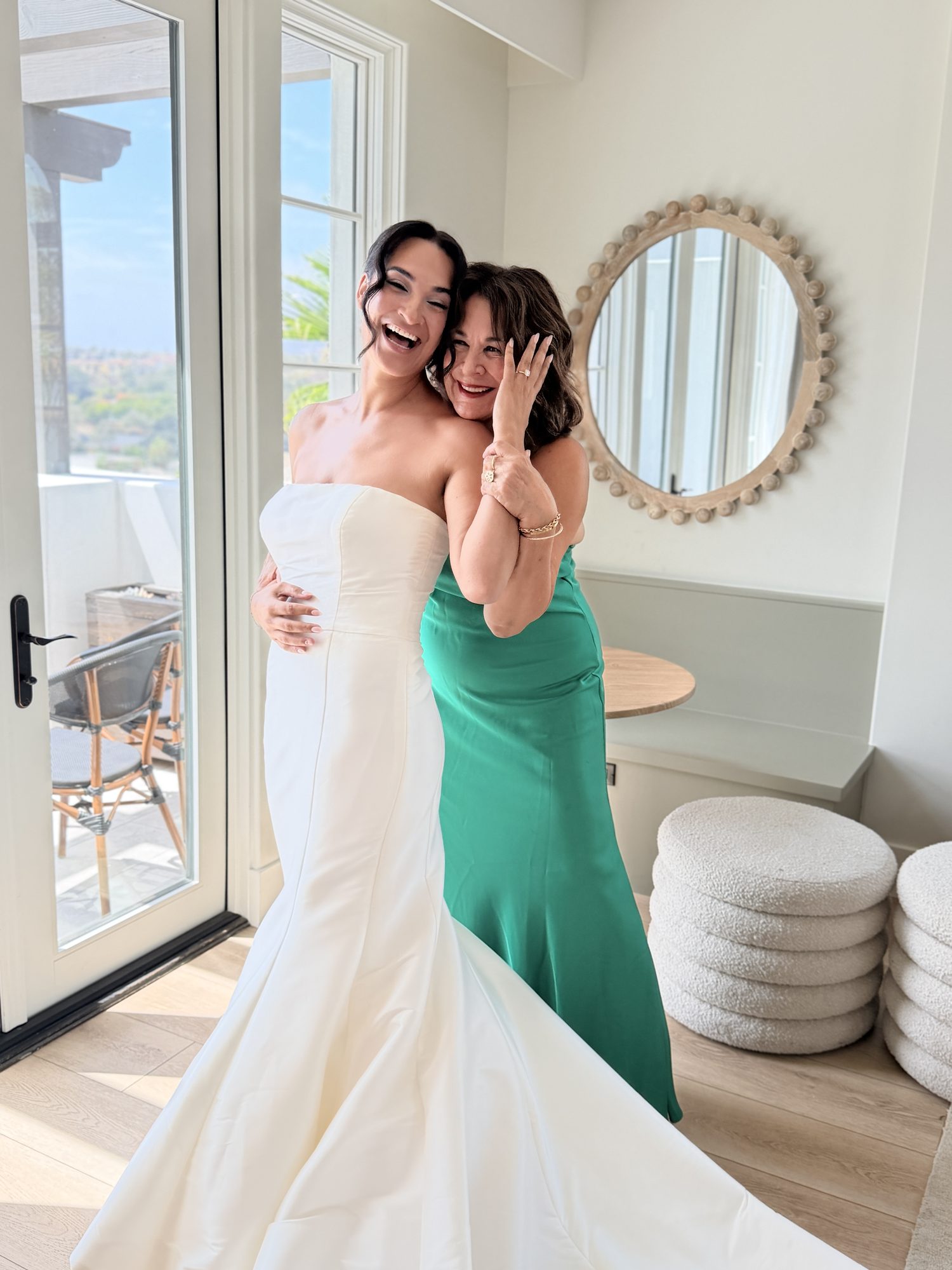 Bride and mother embracing and laughing while getting ready