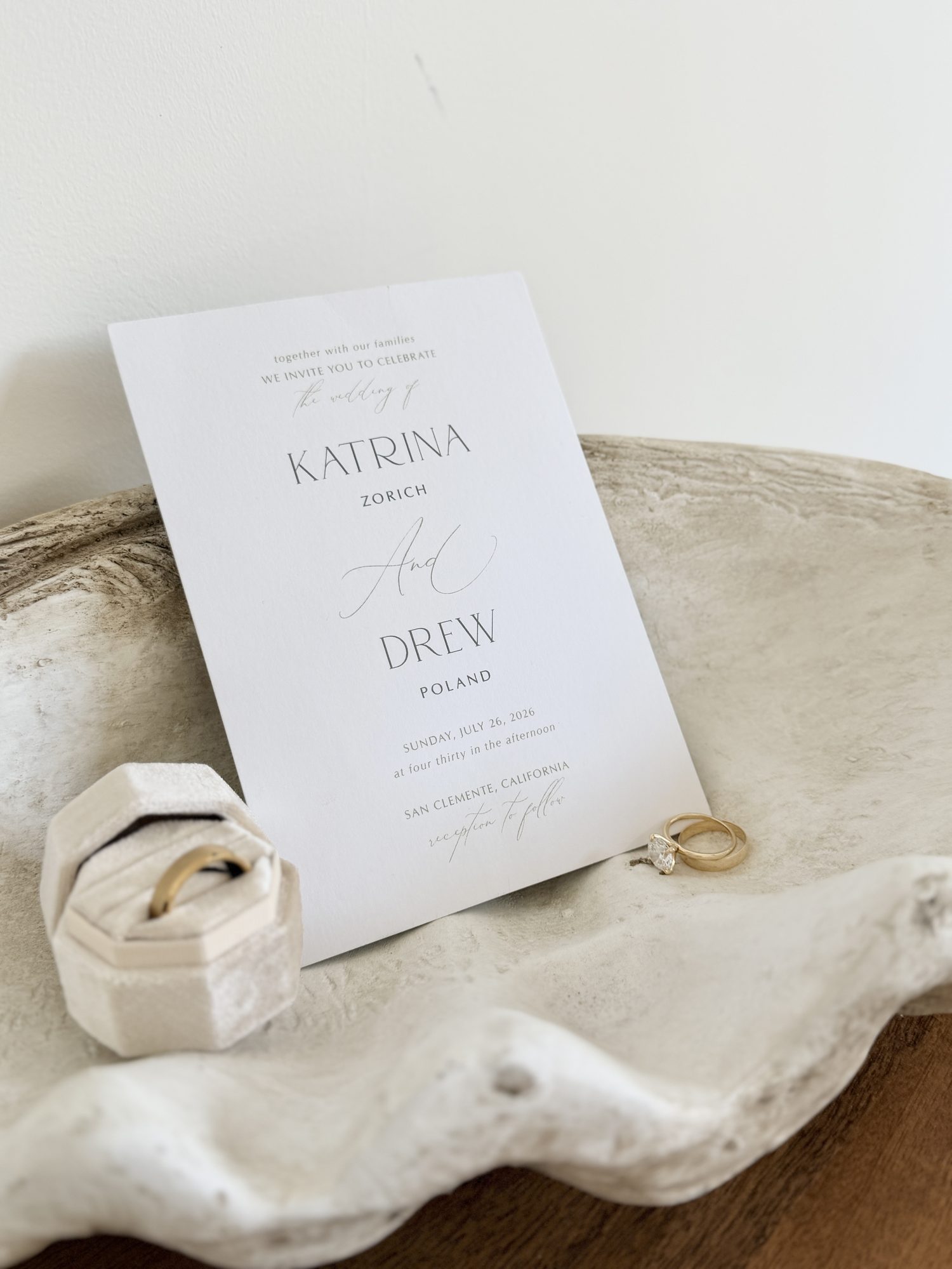 Wedding invitation flat lay with rings on stone dish