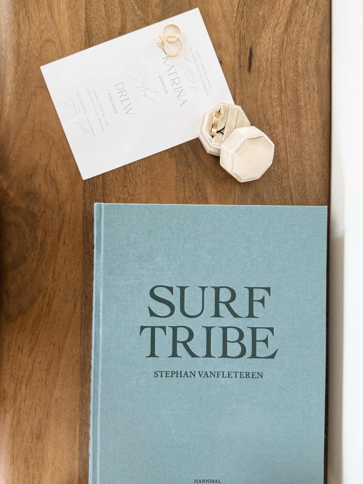 Wedding invitation and rings on a wood table with book