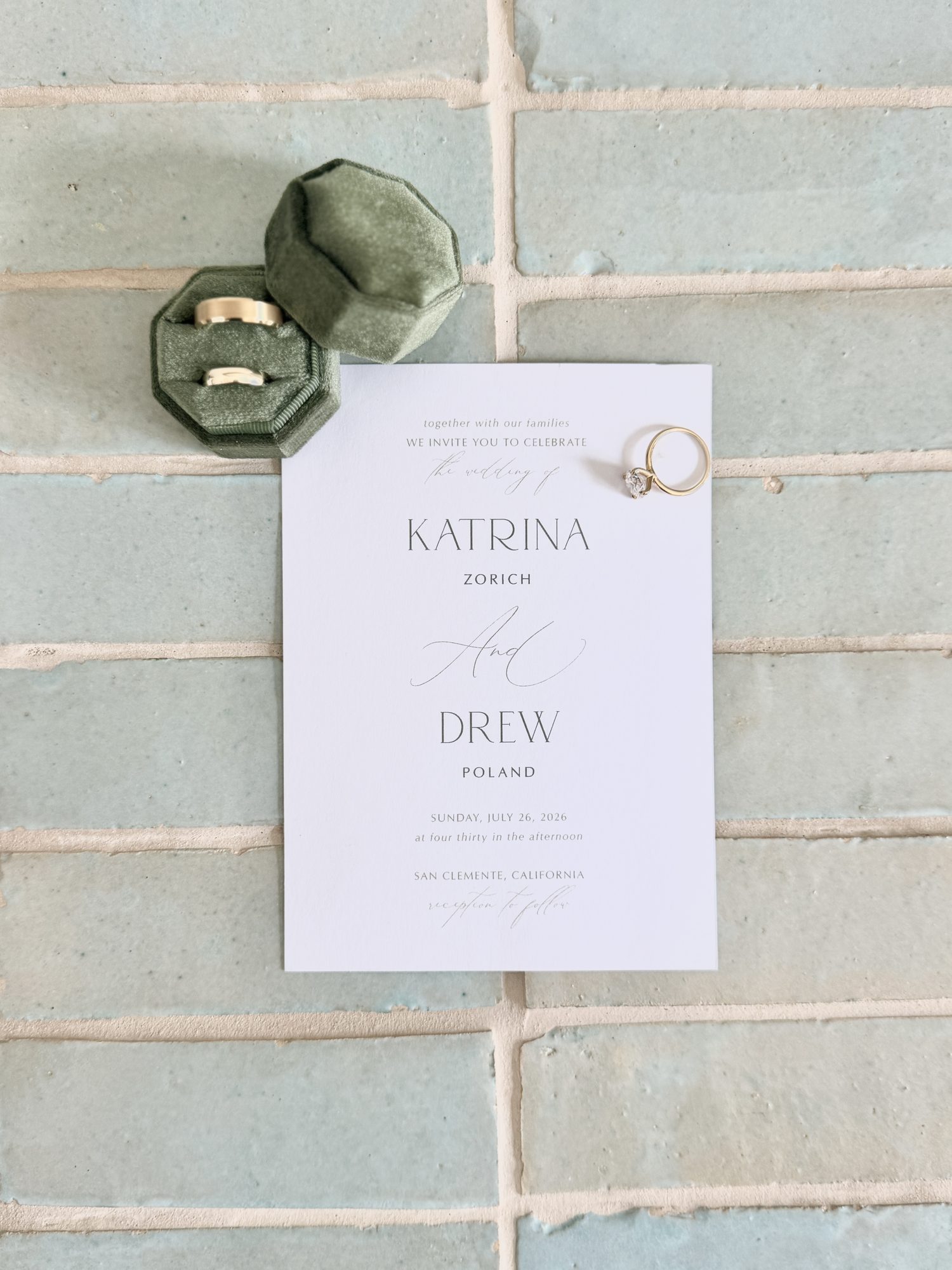 Wedding invitation and rings with velvet ring boxes on tile