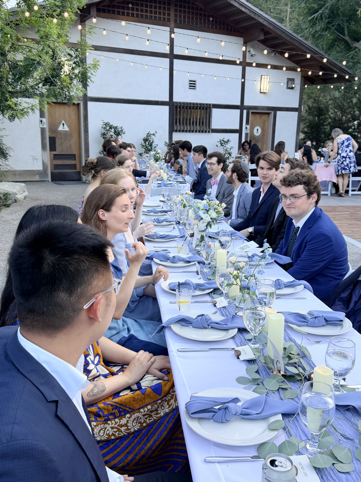 Guests seated at long reception table under string lights