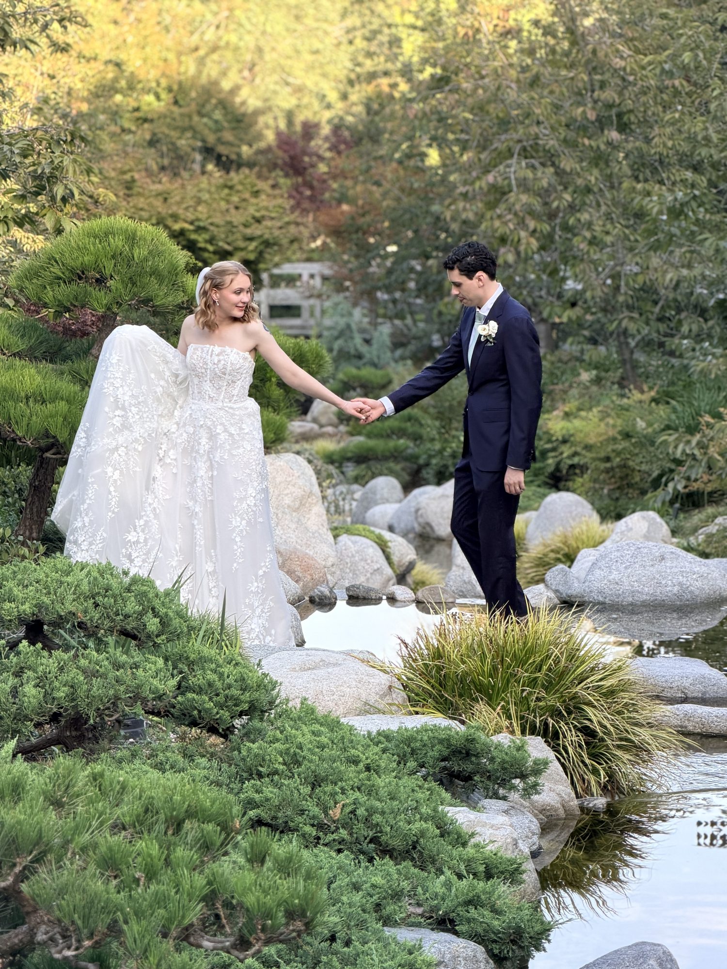 Bride and groom walking hand in hand through Japanese garden