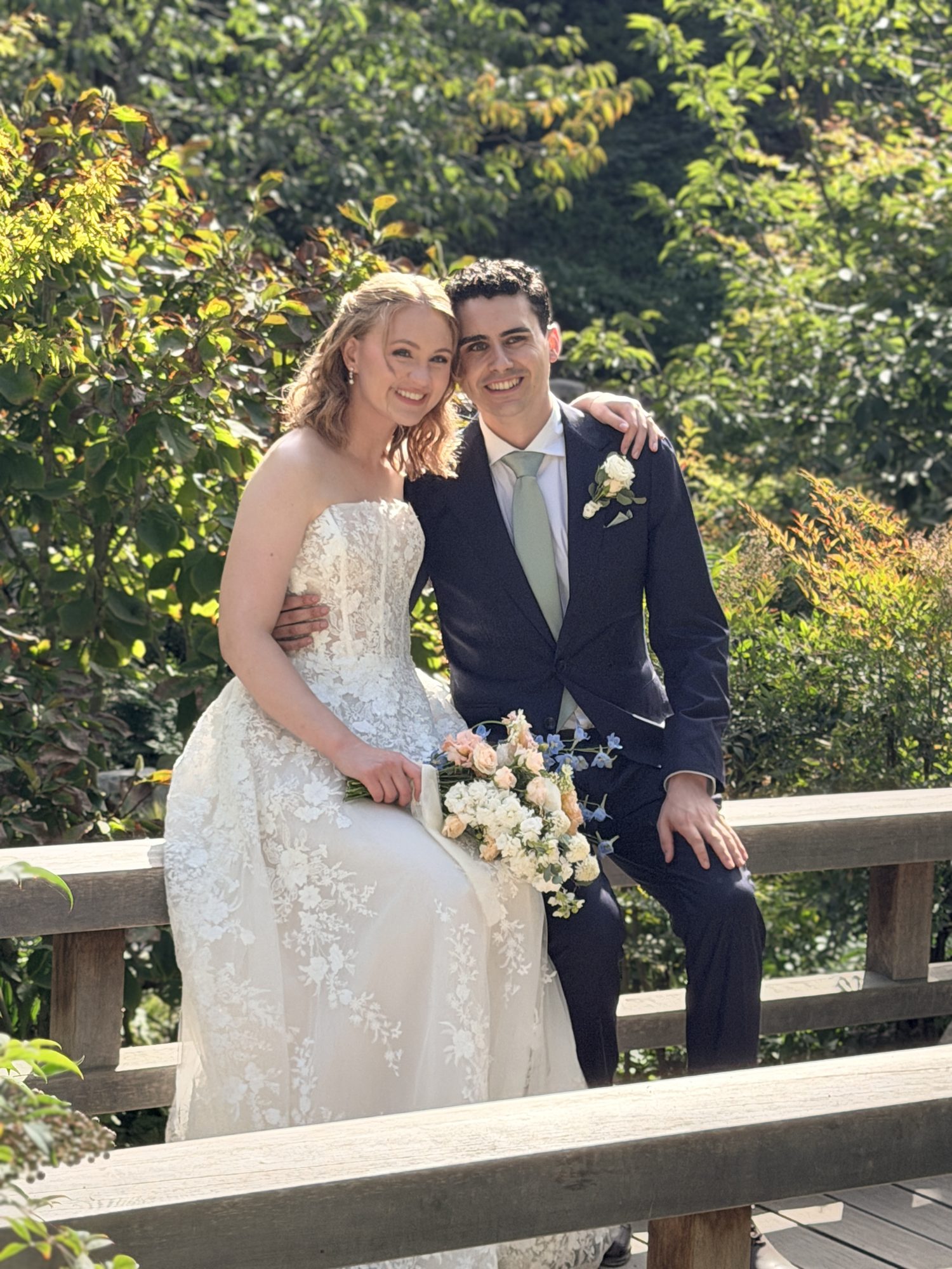 Bride and groom sitting together on a garden bridge