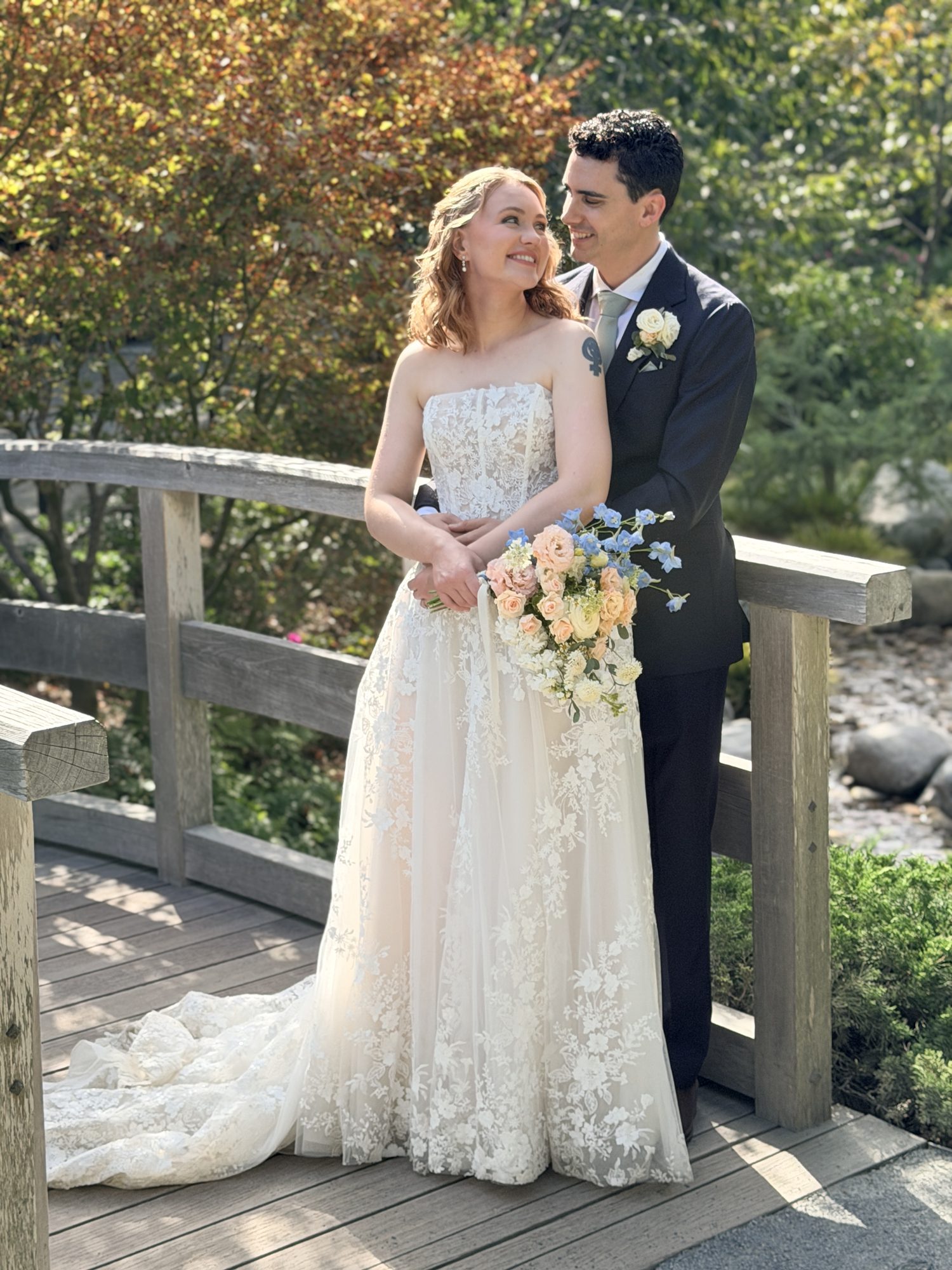 Bride and groom smiling on a garden bridge